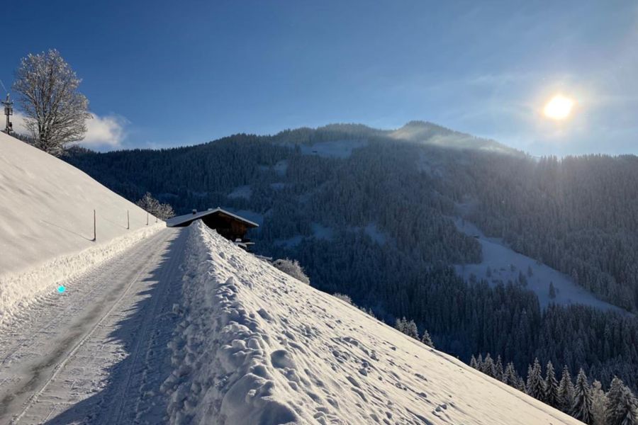 Verschneite Bergstraße zum Chalet mit Blick auf bewaldete Winterberge