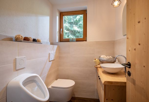 Helles Badezimmer mit WC, Waschbecken, Holzwaschtisch und Fenster