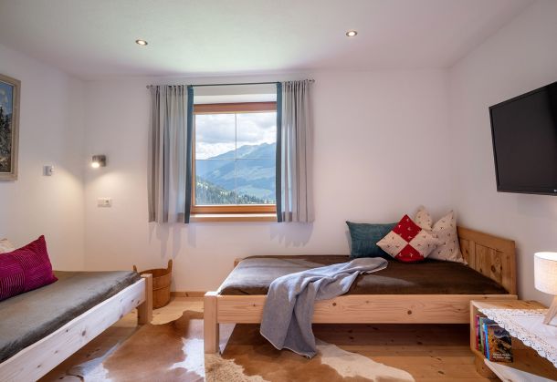 Schlafzimmer mit zwei Einzelbetten, Fernseher und Fenster mit Bergblick